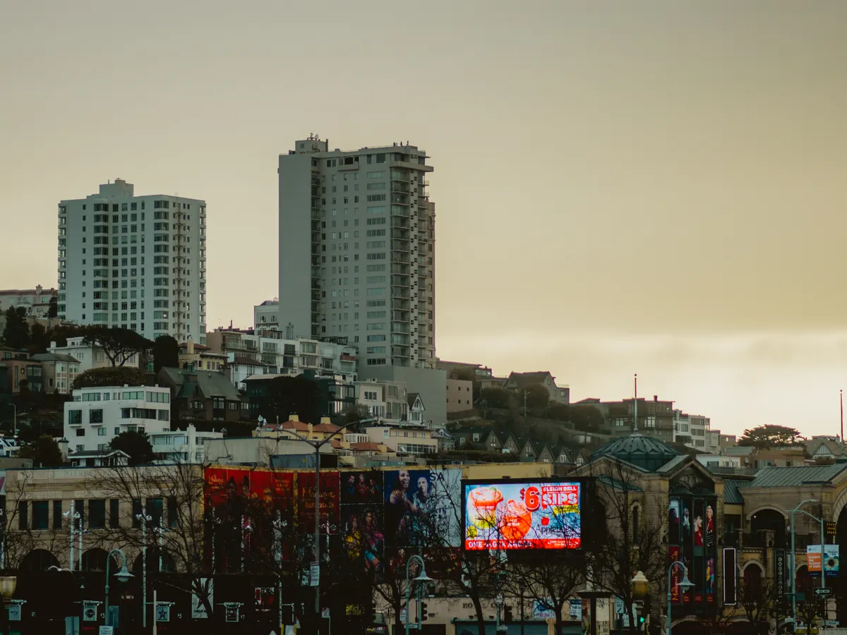 City skyline at dusk with illuminated billboards along the street