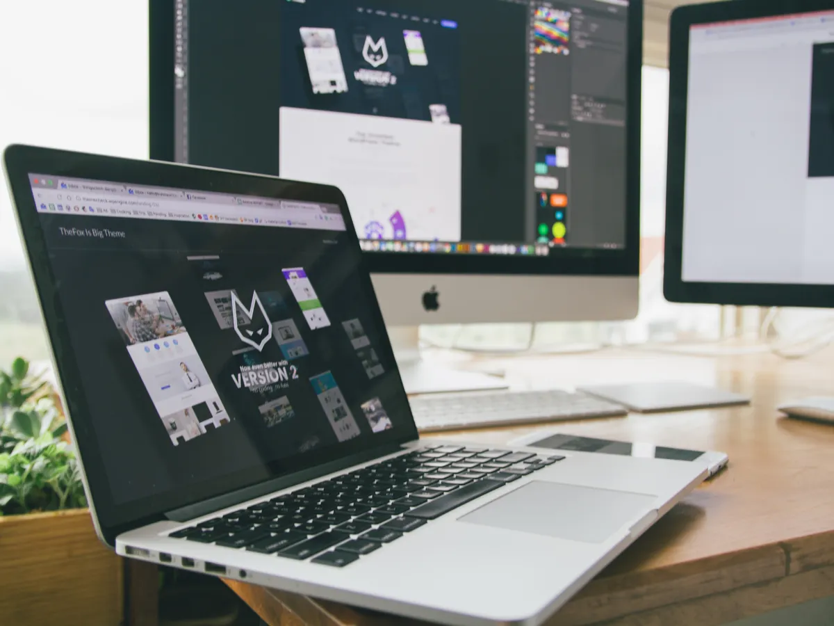 Laptop and desktop monitors showing website layouts in design software