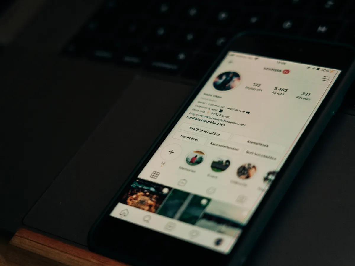 Smartphone showing a social media profile, resting on a laptop